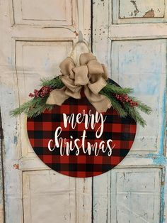 a red and black plaid christmas ornament hanging on a door with a bow