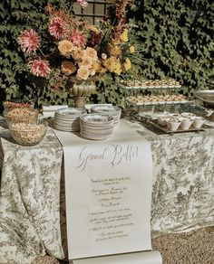 a table topped with plates and cups next to a sign that says grand billi