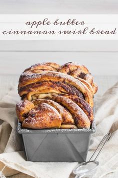 cinnamon swirl bread in a loaf pan on top of a white tablecloth with the words apple butter cinnamon swirl bread