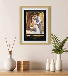 a wedding photo hanging on the wall next to two vases and a potted plant