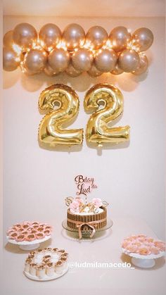 a table topped with cake and balloons next to a number twenty two balloon wall mounted on the wall