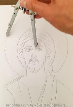 a person is holding scissors and drawing a jesus image on paper with the crucifix in front of them