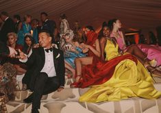 a man in a tuxedo sitting on a bed with other people