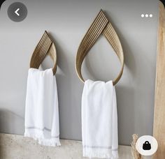 two white towels hanging on the wall next to a wooden towel rack with three hooks