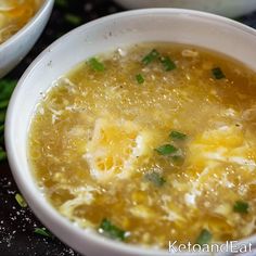 two white bowls filled with soup sitting on top of a black counter next to green onions