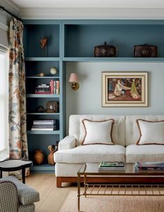 a living room filled with furniture and bookshelves next to a painting on the wall