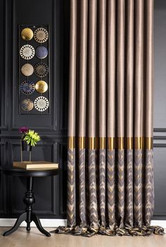 a living room with black walls and gold trimmings on the curtains, along with a small table