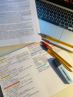 an open laptop computer sitting on top of a desk next to paper and pencils