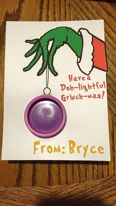 a christmas card with a purple object hanging from it's side on top of a wooden table