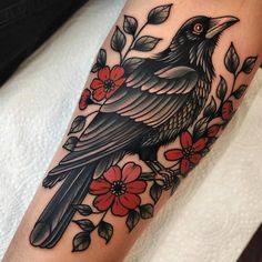 a black bird with red flowers on it's arm