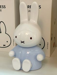 a white rabbit figurine sitting on top of a table next to two boxes