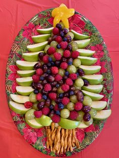 a christmas tree made out of fruits and crackers on a plate with red tablecloth