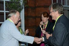 two men shaking hands with other people at an event