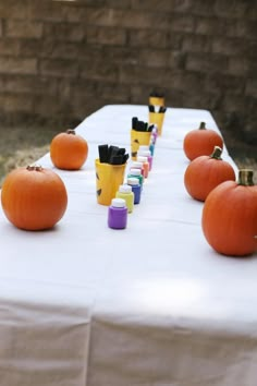 several pumpkins are lined up on a table with markers and cups in front of them