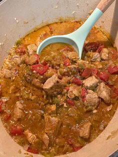 a large pot filled with meat and vegetables next to a wooden spoon on top of a stove