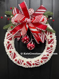 a red and white christmas wreath hanging on the front door with candy canes around it