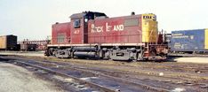 a red and yellow train engine sitting on the tracks next to some other railroad cars