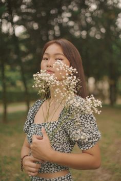 a woman standing in the grass holding flowers