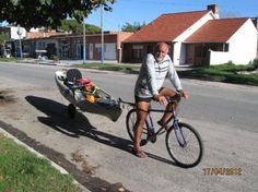 a man riding a bike with a kayak attached to the front and rear wheels