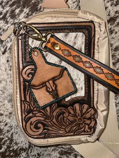 a brown and black purse with a cow design on the front, key chain attached to it