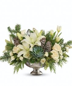 a silver vase filled with white flowers and pine cones