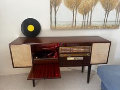 an old radio and record player in a room with a painting on the wall behind it