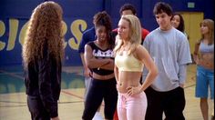 a group of young people standing around each other on a basketball court in front of a blue wall