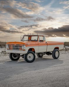 an orange and white truck parked in the sand