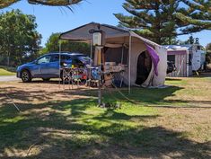 a car parked next to a tent in the middle of a field with other vehicles