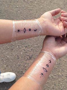 two people holding each other's hands with tattoos on their arms and wristbands