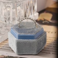 a ring sits in a box on top of a table next to some wine glasses