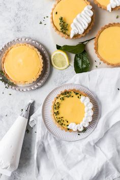 small pies with lemon custard and whipped cream are on the table next to each other