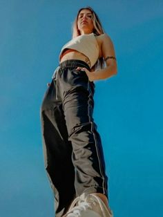 a woman standing on top of a skateboard in front of a bright blue sky