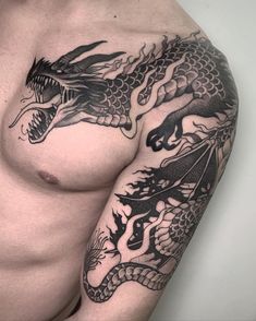 a man's chest with dragon tattoos on his left arm and right arm is covered in black ink