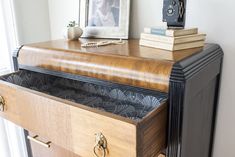 a wooden dresser with drawers and books on top