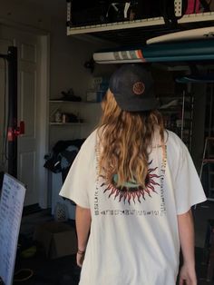 a person with long hair wearing a hat and holding a surfboard above their head