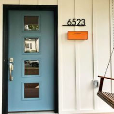 a blue front door with the number 6623 on it next to a porch swing