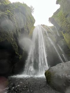 there is a waterfall in the middle of some rocks and moss growing on it's sides