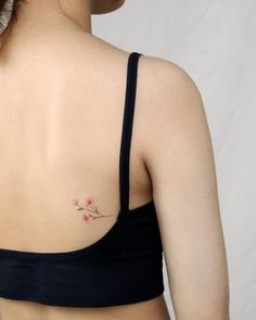 the back of a woman's shoulder with a small flower tattoo on her left side