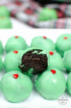 there are green cake balls with red hearts on them and one has a bite taken out