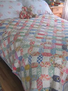 a quilted bedspread with teddy bears sitting on the bed in front of it