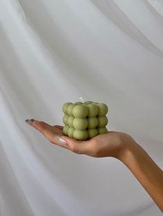 a woman's hand holding a bunch of green grapes in front of a white background