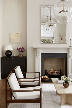 a living room filled with furniture and a fire place in front of a large mirror