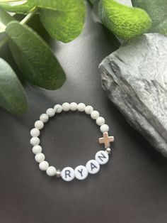 - Sweet baby boy cross bracelet with white howlite gemstone. A perfect baptism or first holy communion bracelet. Personalized boy  for easy gifting. Beaded on high quality stretch cord and secured. - 4mm platinum plated accent beads   4.5mm white howlite   platinum plated cross   acrylic letter beads ‼️Young children MUST be supervised at all times while wearing jewelry. Contains small parts that could be a potential choking hazard. Jewelry should always be removed during sleep. Never leave young children unattended with our products. Supervision is required. It is at the customers discretion for the use of our products.  - Each purchase is sent in a velvet drawstring jewelry bag, making the perfect godchild gift, baptism bracelet, baby first cross bracelet or First Holy Communion gift. - Bracelet Boy, Baptism Bracelet, Godchild Gift, Godson Gifts, Christian Bracelets, Boy Name, Acrylic Letters, Communion Gifts, First Holy Communion