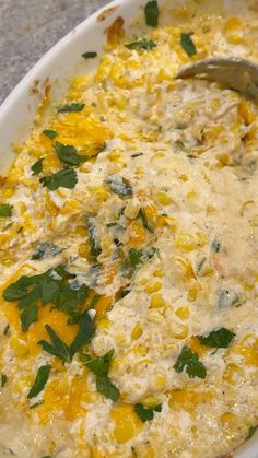 a casserole dish with corn, cheese and parsley on the top is ready to be eaten