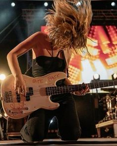 a woman with long hair playing an electric guitar