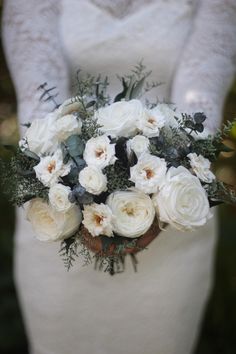 a bride holding a bouquet of white flowers