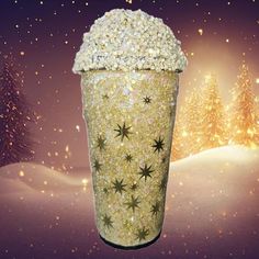 a large cup filled with lots of gold sparkles on top of a snow covered ground