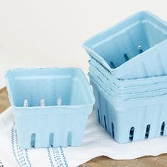 two blue plastic containers sitting next to each other on a white cloth and wooden table