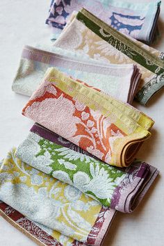 five folded towels sitting on top of each other in different colors and patterns, all lined up together